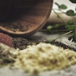 pestle and mortar surrounded by dried herbs and spices